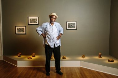 Willie Birch with his “Crawfish Dwelling” sculptures and “Wildflowers or Dwelling” drawings at the New Orleans Museum of Art. William Widmer for The New York Times