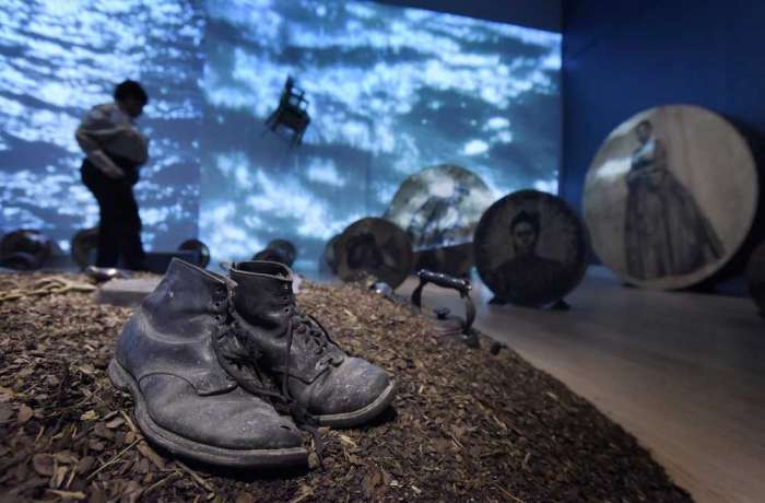Bob Self / Staff Photographer – The installation “Deep River,” which includes a mound of dirt littered with a pair of boots, a frying pan, a bugle, a pistol, a Bible, a tea kettle and an ax is part of the new exhibit, “Whitfield Lovell: Deep River” at the Cummer Museum of Art and Gardens.